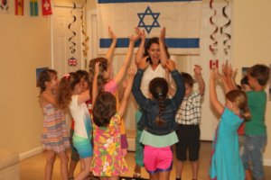 Julia with kids raising hands Israeli flag